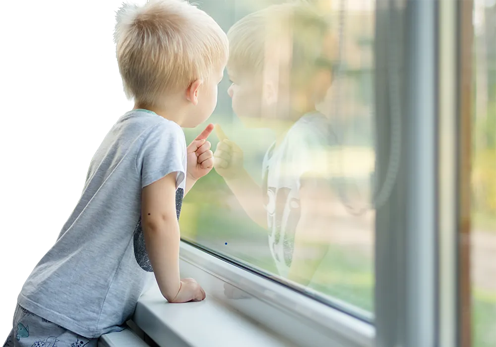 Kleiner Junge der sich in einem Fenster spiegelt und nach draußen zeigt